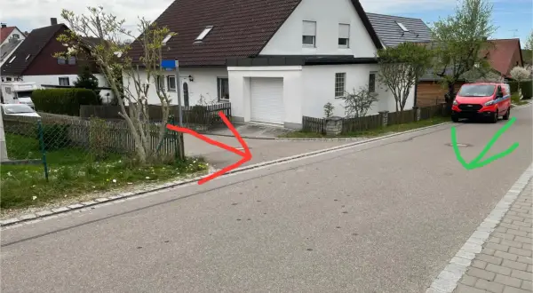 Ein roter Lieferwagen parkt auf der rechten Straßenseite, während rote Pfeile auf eine Einfahrt und ein grüner Pfeil auf einen Gullydeckel zeigen. Das Schild "rechts vor links" ist nicht sichtbar.