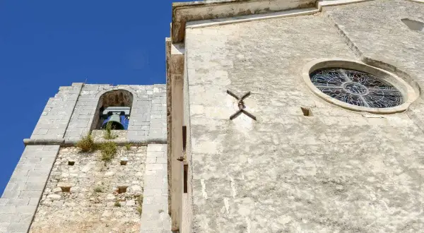 Campanile e rosone di Sant'Elia a Peschici, con il cielo azzurro sullo sfondo.