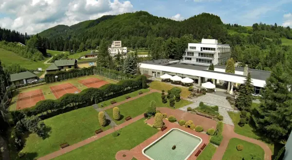 Widok z lotu ptaka na hotel i korty tenisowe w otoczeniu zielonych wzgórz. To Rytro, perła południa, z basenem i zadbanym ogrodem.