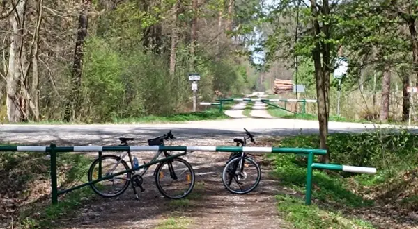 Dwa rowery czekają na odkrycie tras rowerowych Tarnów. Leśna droga zamykana szlabanem zaprasza do przygody.