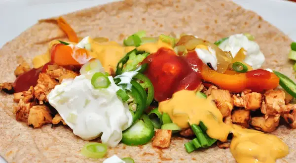 Tortilla garnie de poulet, poivrons, oignons, jalapeños, sauce au fromage et crème aigre. Une délicieuse recette tortilla à déguster !