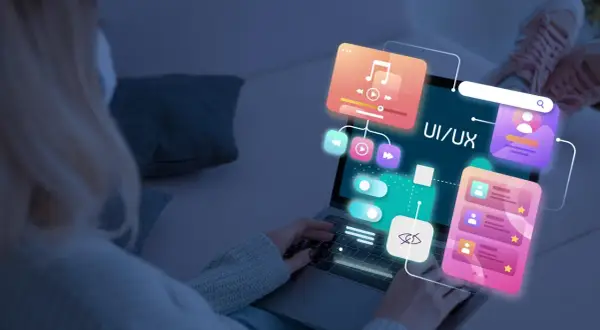 Persona trabajando en el diseño web de una aplicación, con elementos de UI/UX flotando sobre la pantalla.
