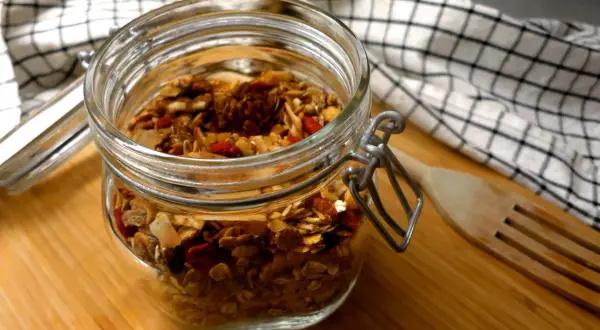 En burk med hemmagjord granola, perfekt som ett bra mellanmål på jobbet. Innehåller nötter, frön och torkad frukt.