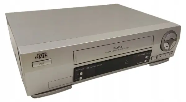 Srebrny vcr JVC z napisem SQPB. Urządzenie posiada przyciski sterujące i slot na kasetę.