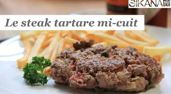 Un steak tartare mi-cuit, savoureux et juteux, servi avec des frites croustillantes et une touche de persil frais. Un délice pour les amateurs de viande.