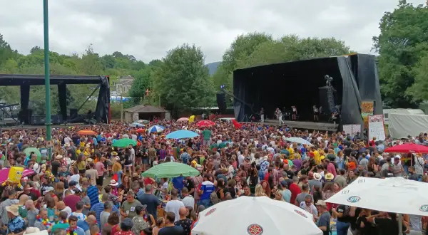 Multitud disfrutando de un concierto al aire libre en Naseiro, Viveiro. Gente bailando y animando bajo un cielo nublado.