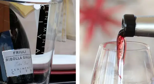 Un bicchiere si riempie di vino rosso, mostrando come si versa il vino. A sinistra, una bottiglia di Ribolla Gialla è in un secchiello.
