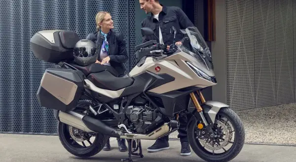 Para zwiedzająca motocykle z automatyczną skrzynią biegów. Nowoczesny turystyczny motocykl Honda z kuframi.