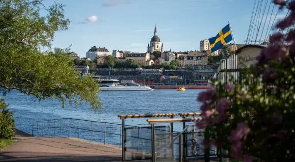 Ein perfekter Blick auf Stockholm für Ihr 4 Tage Stockholm Programm: Die Skyline mit Kirche, die schwedische Flagge und ein Boot auf dem Wasser.