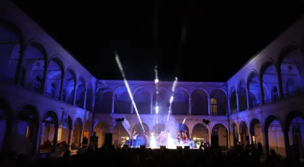 Concerto live sotto gli archi illuminati, un'atmosfera magica per la festa della musica a Brescia.