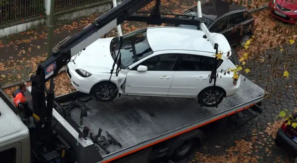 Ein Abschleppdienst hat ein weißes Auto auf einen LKW geladen. Das Auto wurde vorher weggefahren, da es beschädigt war.