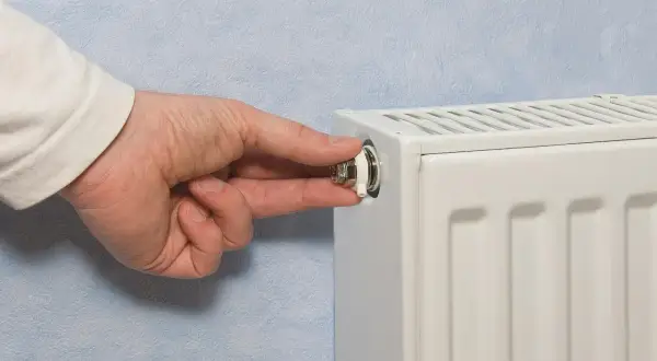 Mano che gira la valvola di uno spurgo termosifone. È il momento di capire quando spurgare i termosifoni per un riscaldamento efficiente.