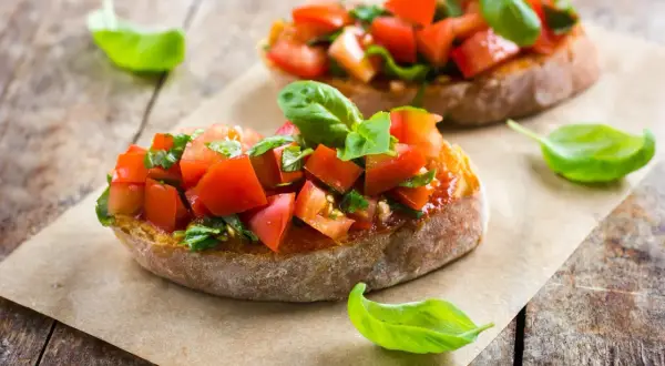 Frische Bruschetta-Rezepte: geröstetes Brot mit Tomaten, Knoblauch und Basilikum, garniert mit Basilikumblättern.