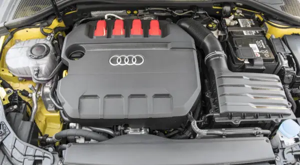 Silnik 2.0 TFSI z czerwonymi elementami i logo Audi. Widoczny akumulator i zbiornik płynu.