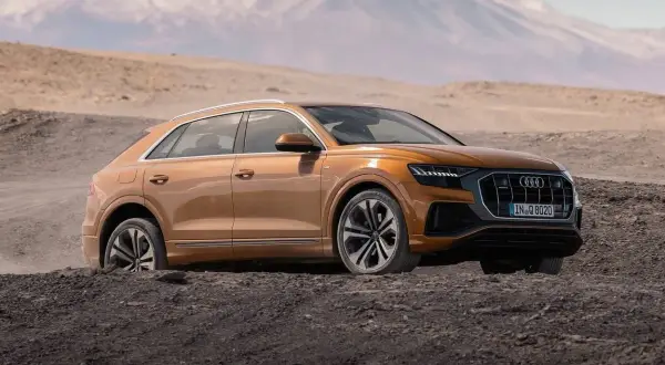 Pomarańczowy Audi Q8 w terenie, gotowy na przygodę. Sprawdź aktualną audi q8 cena i odkryj jego możliwości.