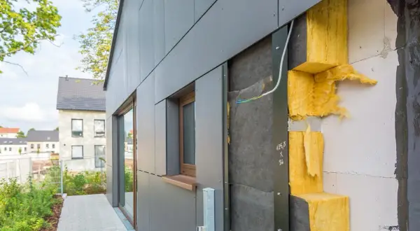 Isolation extérieur : vue rapprochée d'une façade en cours de construction, montrant l'isolant jaune et le revêtement gris. Le prix de cette isolation est un facteur clé pour les propriétaires.