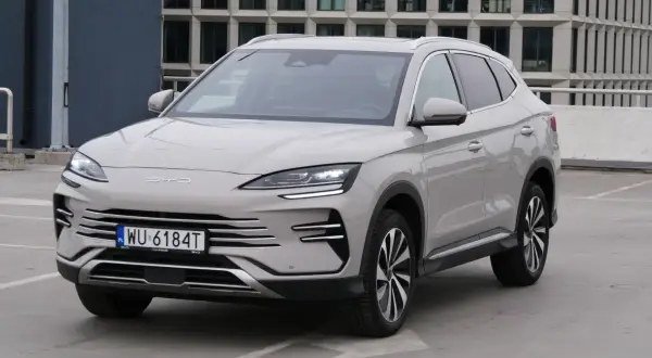 Nowy BYD Song Plus, elegancka hybryda SUV, prezentuje się na parkingu przed nowoczesnym budynkiem.