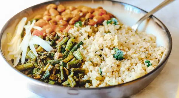 Gesundes Gericht mit Quinoa, Bohnen, grünem Gemüse und Kohlstreifen in einer Schüssel.