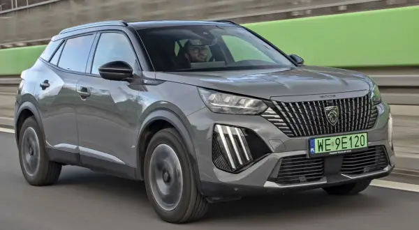Szary Peugeot 2008 na drodze, kierowca w okularach. Sprawdź aktualną peugeot 2008 cena.