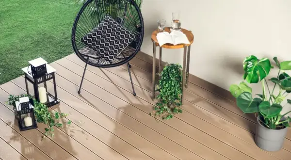 Drewniana deska tarasowa to świetne rozwiązanie, co na balkon zamiast płytek. Wygodny fotel, stolik i latarenki tworzą przytulną atmosferę.