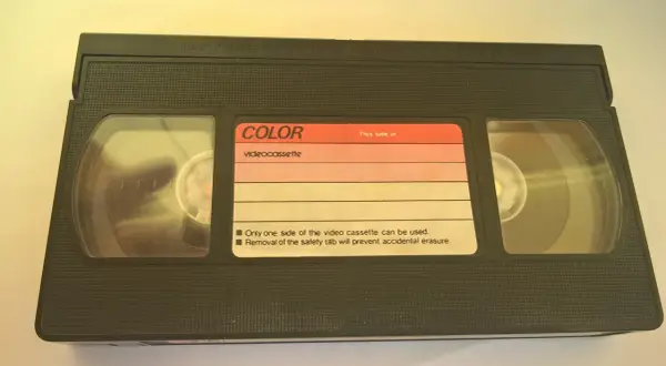 Czarna kaseta wideo z etykietą "COLOR videocassette". Widać dwie rolki taśmy.