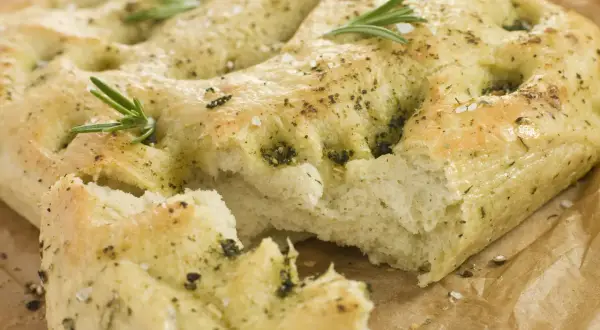 Frisch gebackene italienische Focaccia mit Rosmarin und grobem Salz, auf Backpapier.