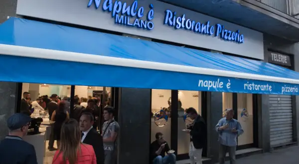 Davanti al ristorante pizzeria "Napule è" a Milano, gente fuori e dentro.