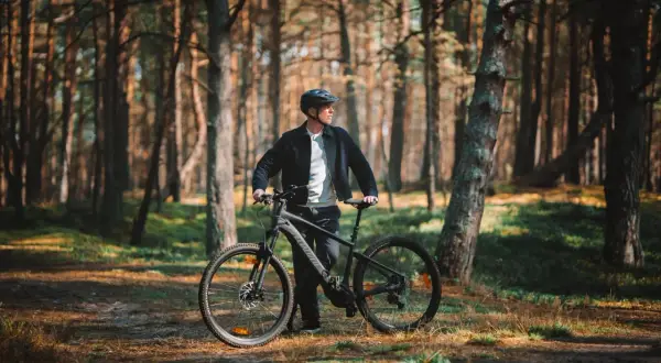 Mężczyzna z rowerem w lesie, gotowy na odkrywanie tras rowerowych Łeba.