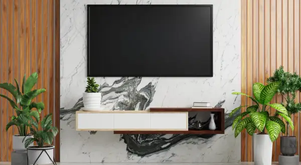 Elegancka ściana z telewizorem na tle marmuru i drewna. Wokół zielone rośliny tworzą przytulną atmosferę.