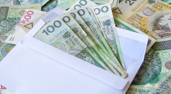Koperta z banknotami 100 zł, część większej kwoty, jak darowizna od rodziców 50 tys. zł.