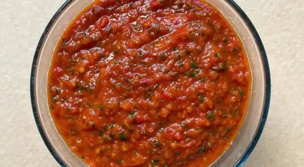 Bagnetto rosso piemontese in una ciotola di vetro, un condimento saporito e piccante, perfetto per accompagnare bolliti e carni.