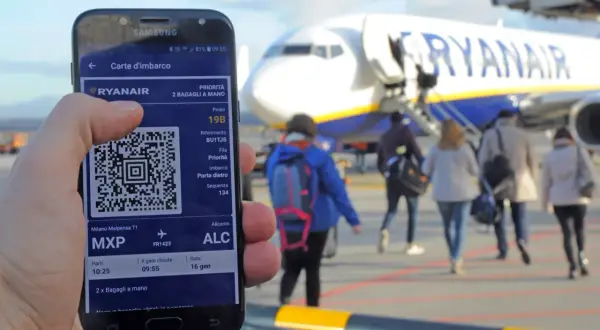 Telefon z kartą pokładową Ryanair i samolot na tle.