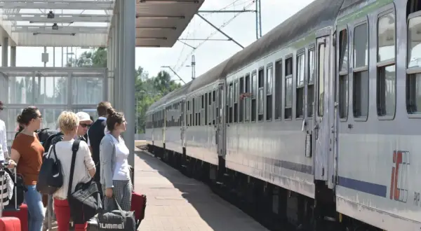 Ludzie z bagażami czekają na pociąg PKP. Podróżowanie pkp taniej z bliskimi to świetny pomysł na wakacje.