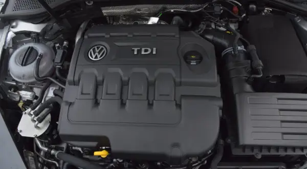 Silnik 2.0 TDI 190 KM. Widok na pokrywę silnika z logo VW i napisem TDI. W tle zbiornik płynu chłodniczego.