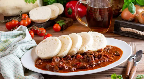 Gulasz z knedlikami, klasyka kuchni czeskiej, podany z piwem i świeżymi pomidorkami.