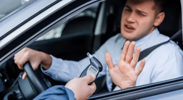 Mann im Auto wehrt sich gegen Alkoholtest. 1,1 Promille Strafe droht.