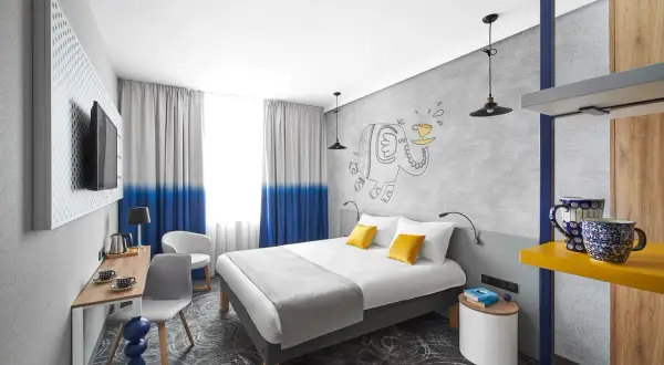 Pokój w hotelu Ibis z łóżkiem, biurkiem i rysunkiem słonia.