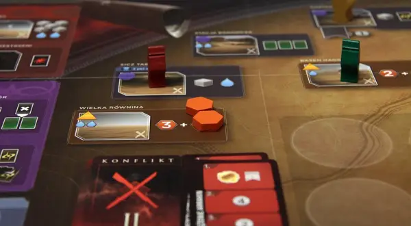 Fragment planszy do gry "Diuna: Imperium". Czerwone i zielone pionki walczą o zasoby na pustynnej mapie.