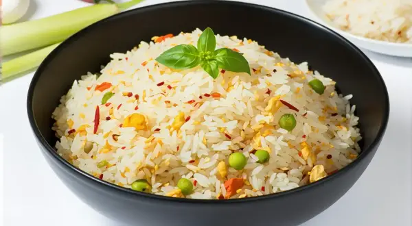 Un bol de riz pilaf aux petits pois, œuf et piment, garni d'une feuille de basilic.