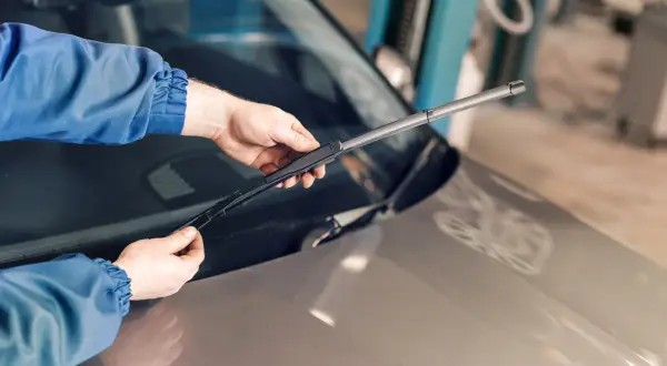 Mains tenant un essuie-glace de voiture, prêt à remplacer ceux qui font du bruit.