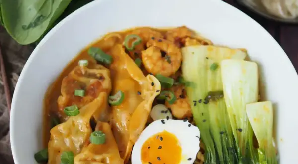 Schüssel mit Ramen, Garnelen, Gyoza, Pak Choi, Ei und Frühlingszwiebeln. Köstliche Ramen-Toppings!