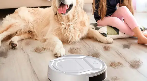 Un robot aspirador limpia el pelo de perro en un hogar mientras una niña acaricia a su mascota.