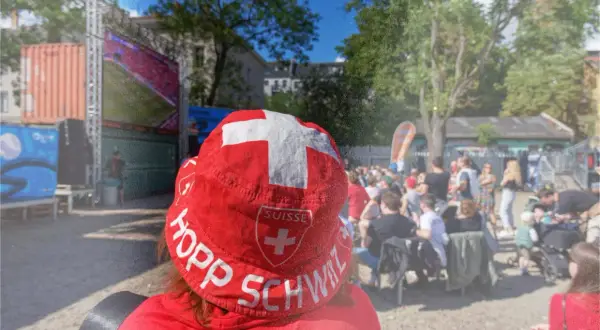Public viewing Berlin: Ein Fan mit Schweizer Hut jubelt bei einem Fußballspiel.