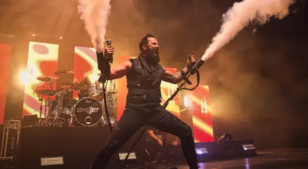 Skillet na koncercie w Warszawie, wokalista John Cooper strzela dymem z ręki.