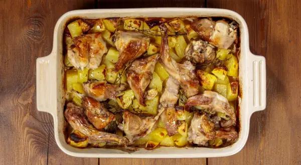 Coniglio ripieno al forno con patate, dorato e profumato, pronto per essere gustato.