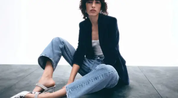Frau in lässigen Jeans, Samtblazer und glitzernden Mules. Ein Look, der casual chic perfekt verkörpert.