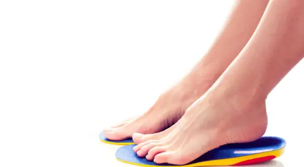 Piedi femminili appoggiati su ortesi per piede colorate, per un comfort e supporto ottimali.