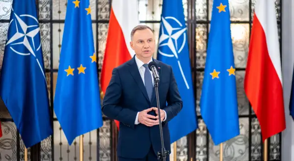 Prezydent Polski przemawia na tle flag NATO i UE. Choć nie wiemy, ile zarabia prezydent Polski, jego pensja jest publicznie dostępna.