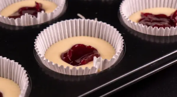 Nadziewane dżemem muffinki w papierowych foremkach w blaszce.