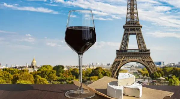 Ett glas rött vin och ost framför Eiffeltornet, som används för att visa upp Paris kultur och skönhet.